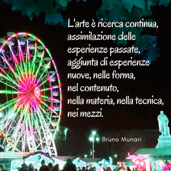 Una fotografia notturna di una ruota panoramica illuminata con colori vivaci (rosa, verde, giallo). Sulla destra, sovrapposto all'immagine, un testo bianco riporta una citazione di Bruno Munari sull'arte come ricerca continua. In basso a destra si vede la statua di un monumento illuminata e la firma di Bruno Munari.